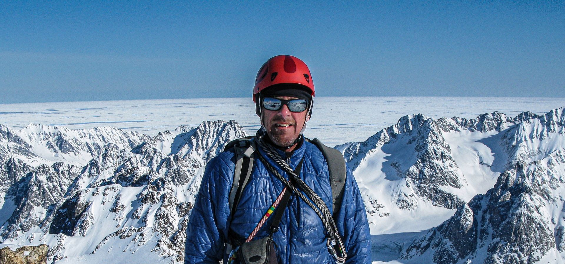Simon Yates stands in front of a snowy mountain background
