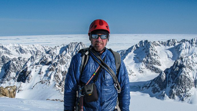 Simon Yates stands in front of a snowy mountain background